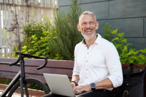 Happy guy. Successful modern middle aged businessman in stylish suit smiling aside while working on