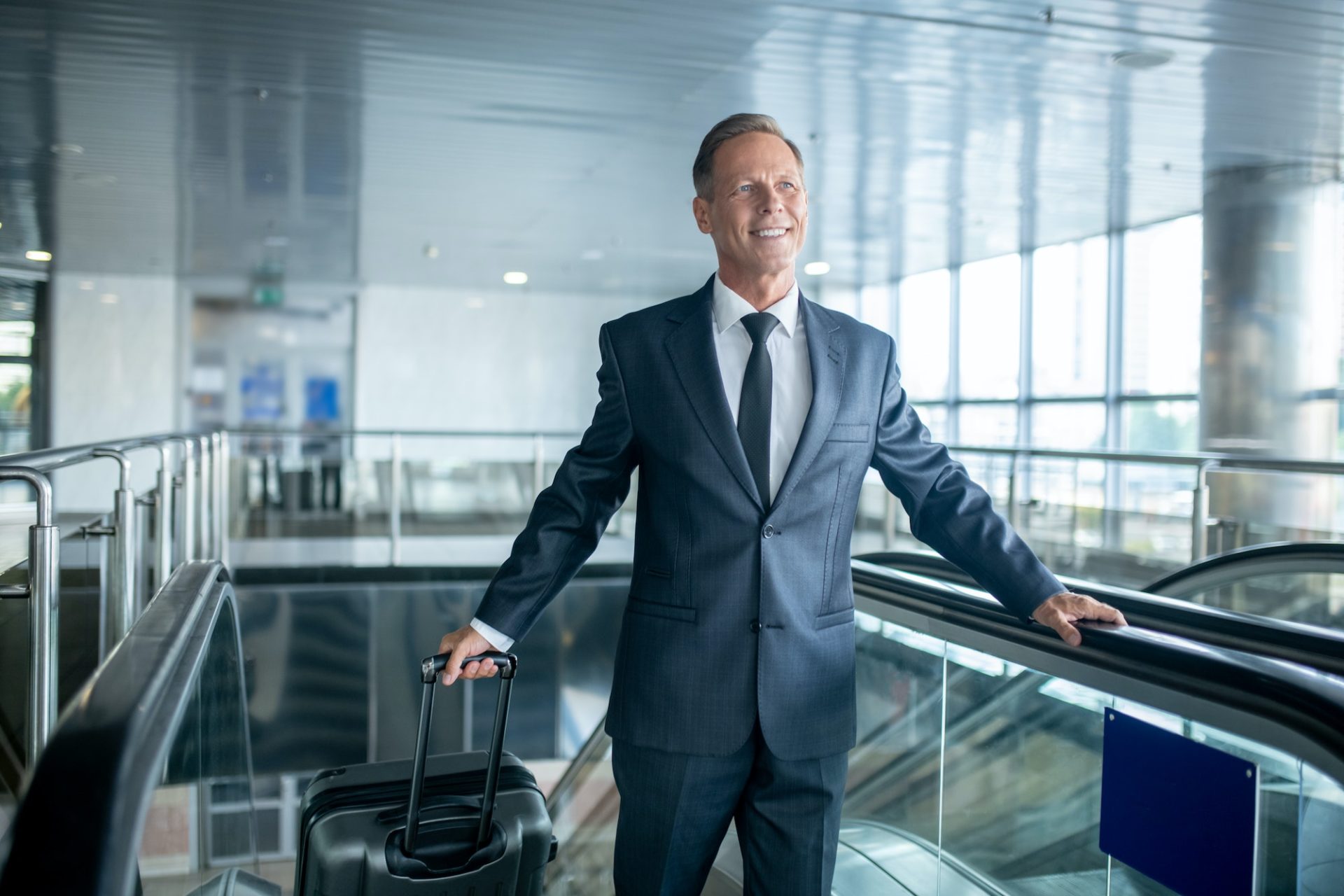 Smiling handsome middle-aged guy stepping off the escalator