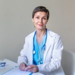 Smiling middle-aged female professional doctor looking at camera at workspace