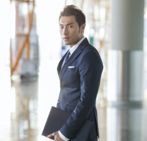 Young businessman walking in airport with suitcase and laptop